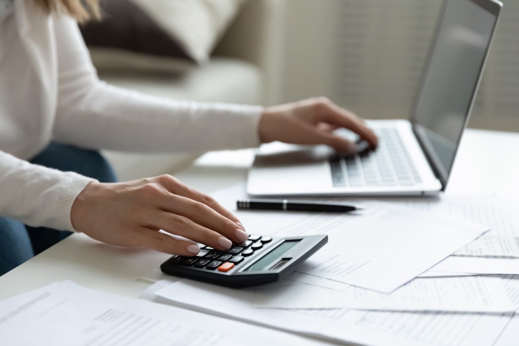Mains d’une femme réalisant des opérations sur sa calculatrice afin de calculer sa réduction d’impôts